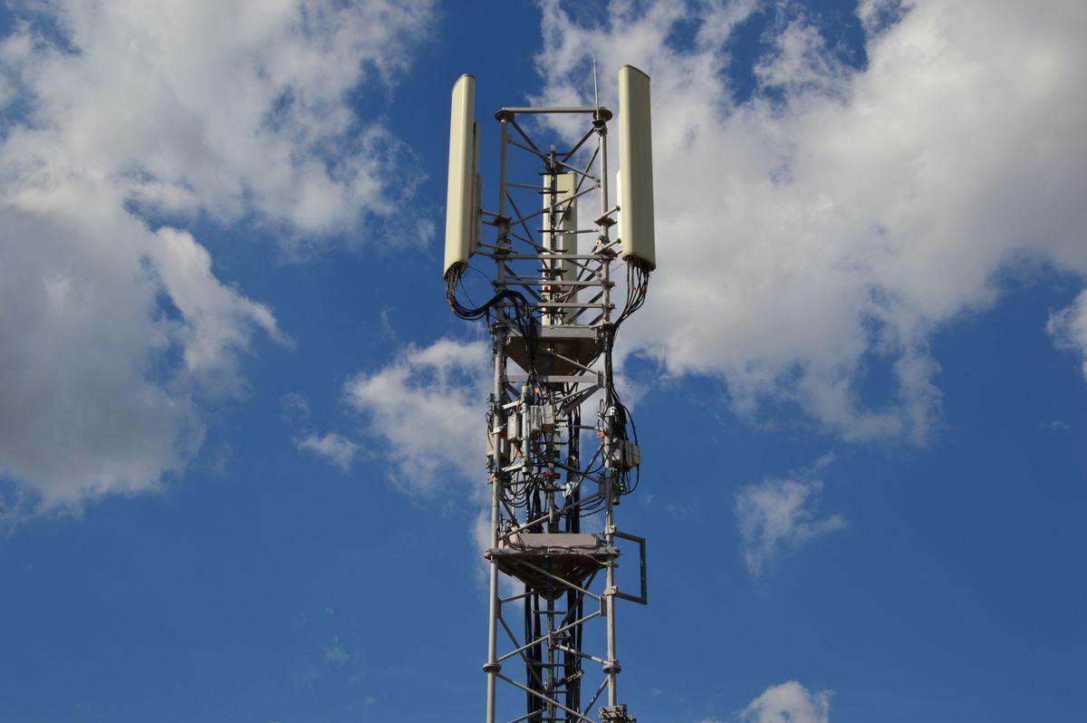 青空にそびえる携帯電話の基地局のアンテナ塔
